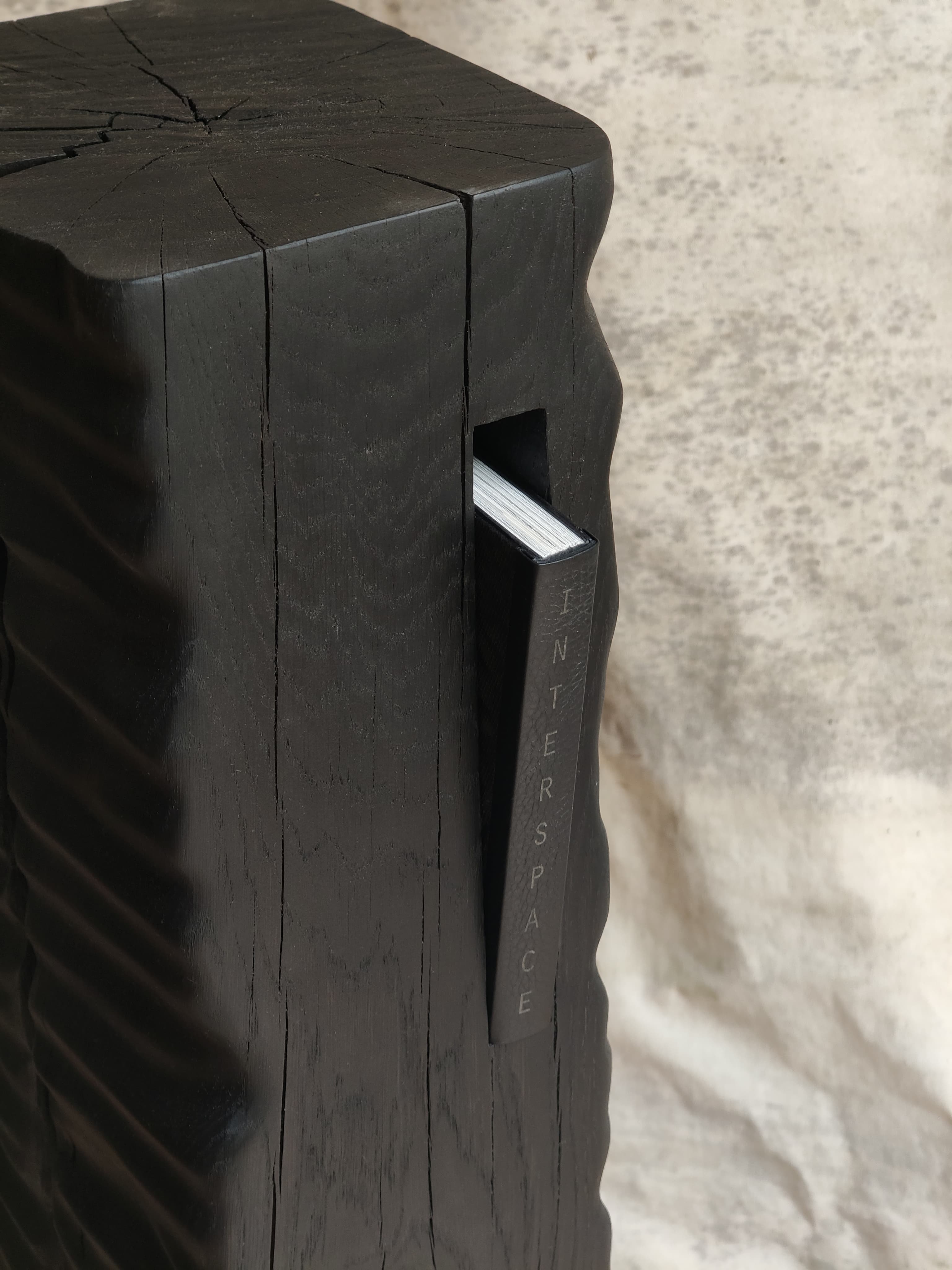 Detail of Monolith Library II by Camille Tan showing ebonised oak surface and a book inside 